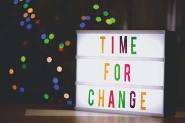 Está escrito em uma tela com letras coloridas "Time For Change"